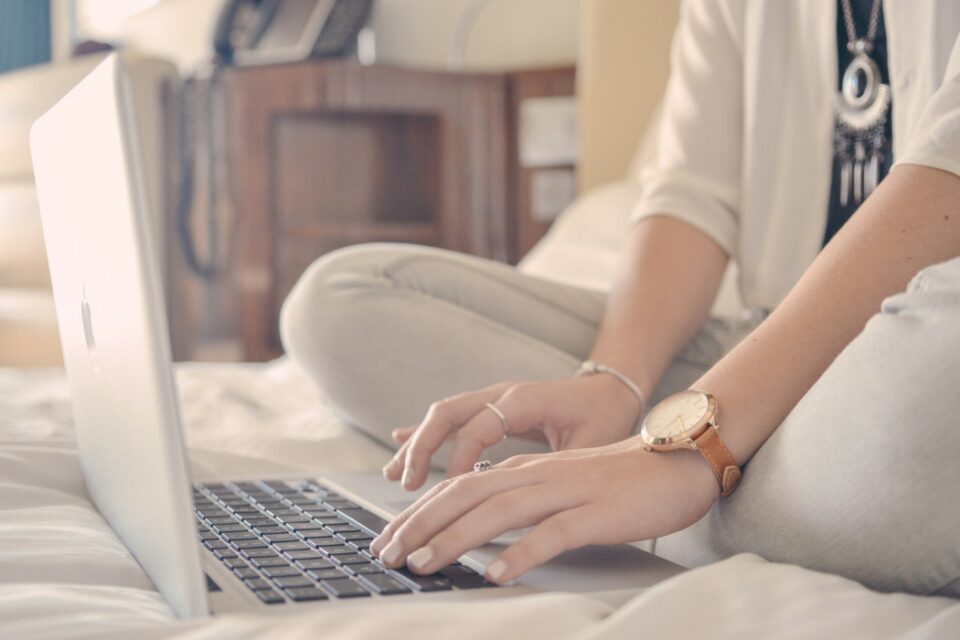 woman typing on laptop in bed