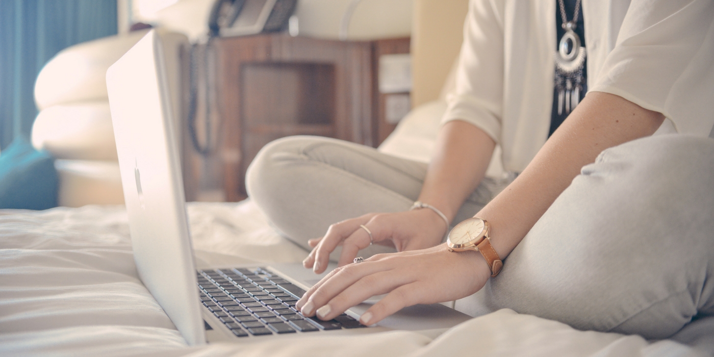 woman typing on laptop in bed